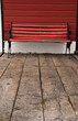 A red wood bench against a red wall at an old railway station
