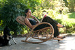 Donna legge su sedia a dondolo in giardino Donna legge su sedia a dondolo in giardino