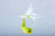 green chilli thrown in water with gray background