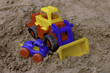 Plastic toy tractor on the sand with the car Plastic toy tractor on the sand with the car