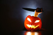 Hand with knife raising from glowing pumpkin lantern