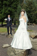 Foto: bride standing on top of a rock with blurred groom in the back bride standing on top of a rock with blurred groom in the back