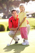 Father Teaching Daughter To Play Golf On Putting On Green
