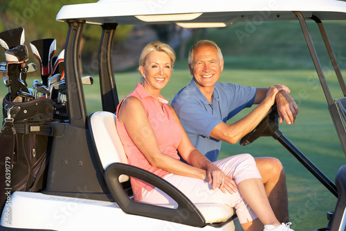 Photo: Senior Couple Riding In Golf Buggy On Golf Course Senior Couple Riding In Golf Buggy On Golf Course