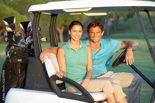 Photo: Couple Riding In Golf Buggy On Golf Course Couple Riding In Golf Buggy On Golf Course