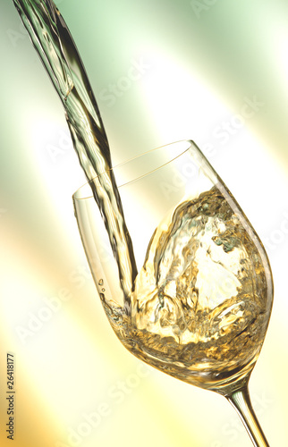 Foto: Pour white vine into glass with light background. Pour white vine into glass with light background.