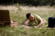 A middle aged man lying on the grass, having a beer