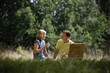 A middle aged couple sitting on the grass, having a drink