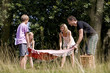 A family laying a picnic blanket on the grass