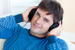 cheerful man listening music with headphones on lying in the liv