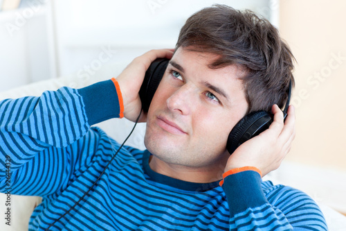 Photo: attractive young man listening music sitting in the living-room attractive young man listening music sitting in the living-room