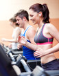 Beautiful female athlete standing on a running machine listening Beautiful female athlete standing on a running machine listening
