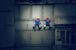 Painters in hard hats and harnesses hanging building wall Painters in hard hats and harnesses hanging building wall