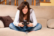 Young female playing video-games concentrating on sofa at home