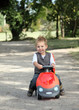Enfant jouant dehors avec sa voiture rouge