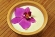 Orchidee schwimmt in Milch in einer Holzschale