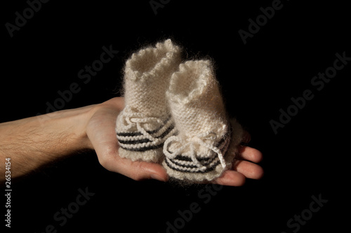Photo: papa's hand with baby's bootees papa's hand with baby's bootees