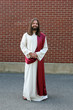 Photo: Man in Jesus robe and sash next to brick wall Man in Jesus robe and sash next to brick wall