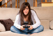 Young female playing video-games concentrating on sofa at home