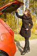 The girl closes a luggage place of the red car