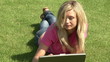Beautiful woman using laptop lying in the garden