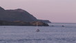 View of a sailboat arriving in the bay at sunset
