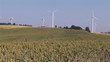 View of turning wind turbines standing in a field