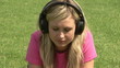 Woman listening music on the grass using headphones
