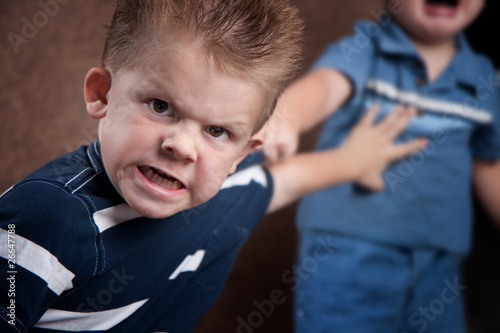 Photo: Angry little boy glaring and fighting with his brother Angry little boy glaring and fighting with his brother