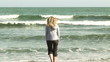 Woman on the beach checking water temperature with her feet