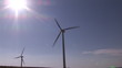 Below view of two wind turbines turning during a sunny day