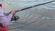 Close up of a woman winding the thread of her fishing rod