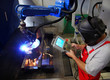 Foto: Schweisser bedient Roboter Schweisser bedient Roboter