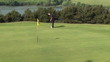 Golfer putting the ball in the last hole during competition
