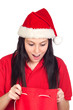 Surprised girl with Christmas hat looking on the sack
