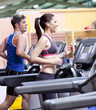 Photo: Healthy couple running on a treadmill in a sport centre Healthy couple running on a treadmill in a sport centre