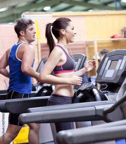 Photo: Healthy couple running on a treadmill in a sport centre Healthy couple running on a treadmill in a sport centre
