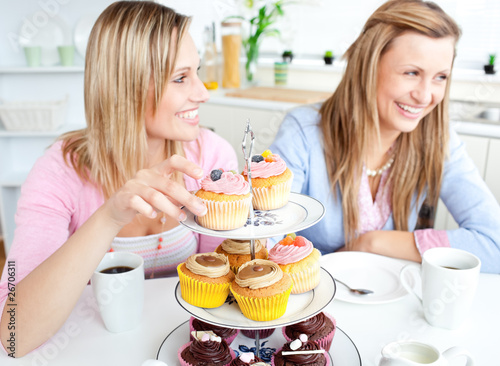 Foto: Women having fun eating cupcakes in the kitchen Women having fun eating cupcakes in the kitchen