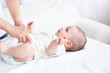 Close-up of a young mother changing the nappy of her baby lying