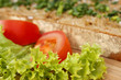 Eine Scheibe Brot auf einem Holzbrett mit Tomaten und Salat