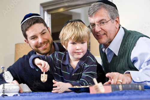 Photo: Boy with father and grandfather spinning dreidel Boy with father and grandfather spinning dreidel