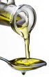 Olive oil flowing from carafe into the spoon.