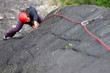 Young woman with helmet climbing basalt rock