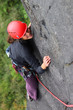 Smiling woman with helmet climbing basalt rock