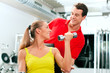 Woman with trainer and dumbbells in gym