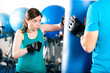 Kick-Boxerin mit Trainer am Sandsack