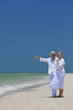 Happy Senior Couple Pointing To Sea on Tropical Beach
