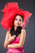 Beautiful brunette woman in red tulle hat looking at camera Beautiful brunette woman in red tulle hat looking at camera