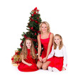 Mother with children sit near Christmas tree.