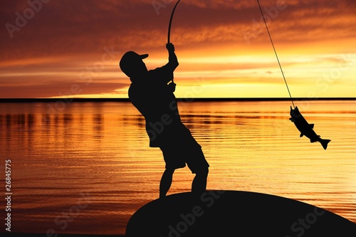 Photo: fisherman with a catching fish on sunrise background fisherman with a catching fish on sunrise background